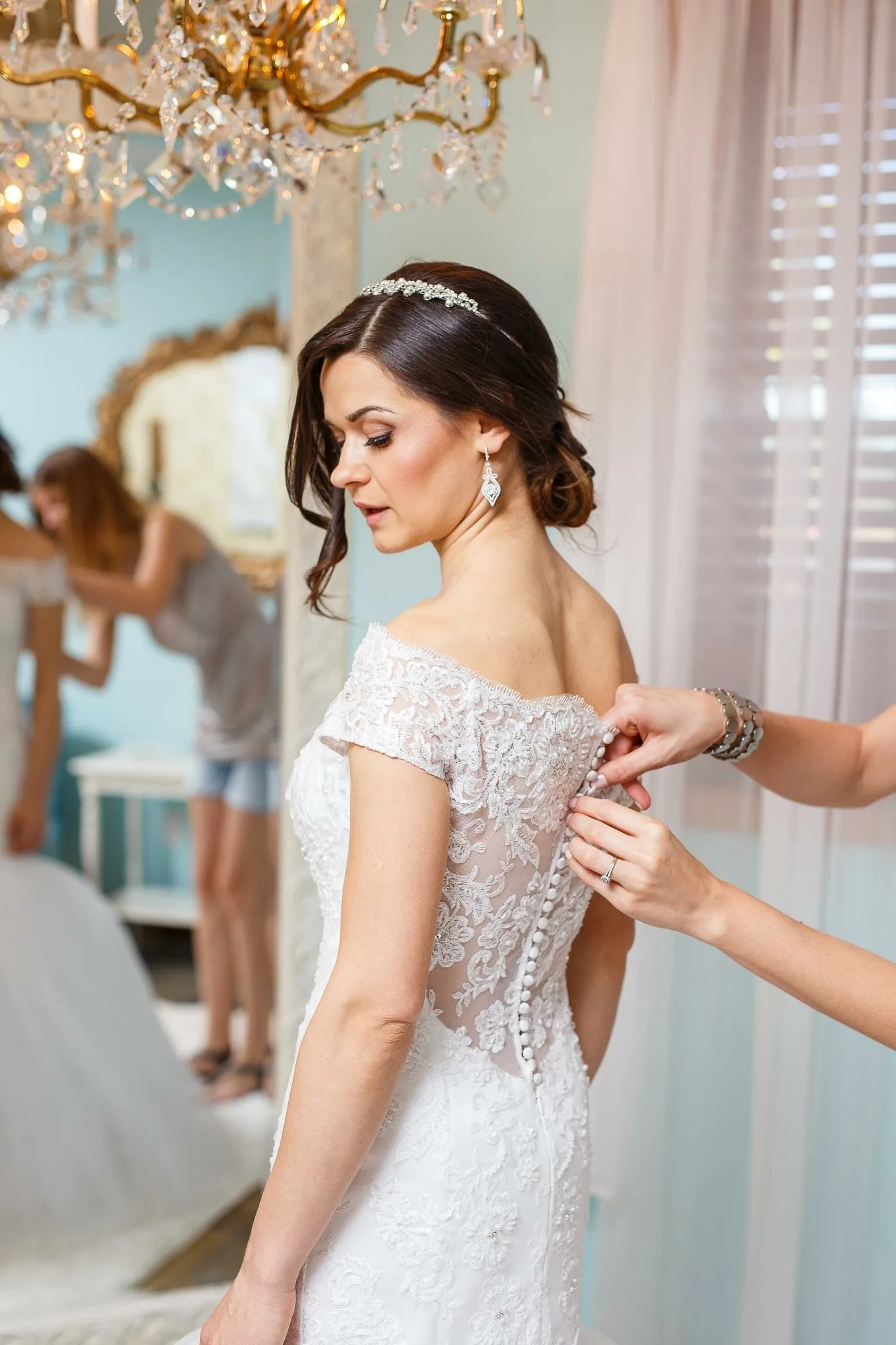 bride getting dressed lace gown mountain view manor - Mountain View Manor Bride in an off-shoulder lace wedding gown being buttoned up by a bridesmaid in the bridal suite at Mountain View Manor wedding venue in Enumclaw Washington near Seattle