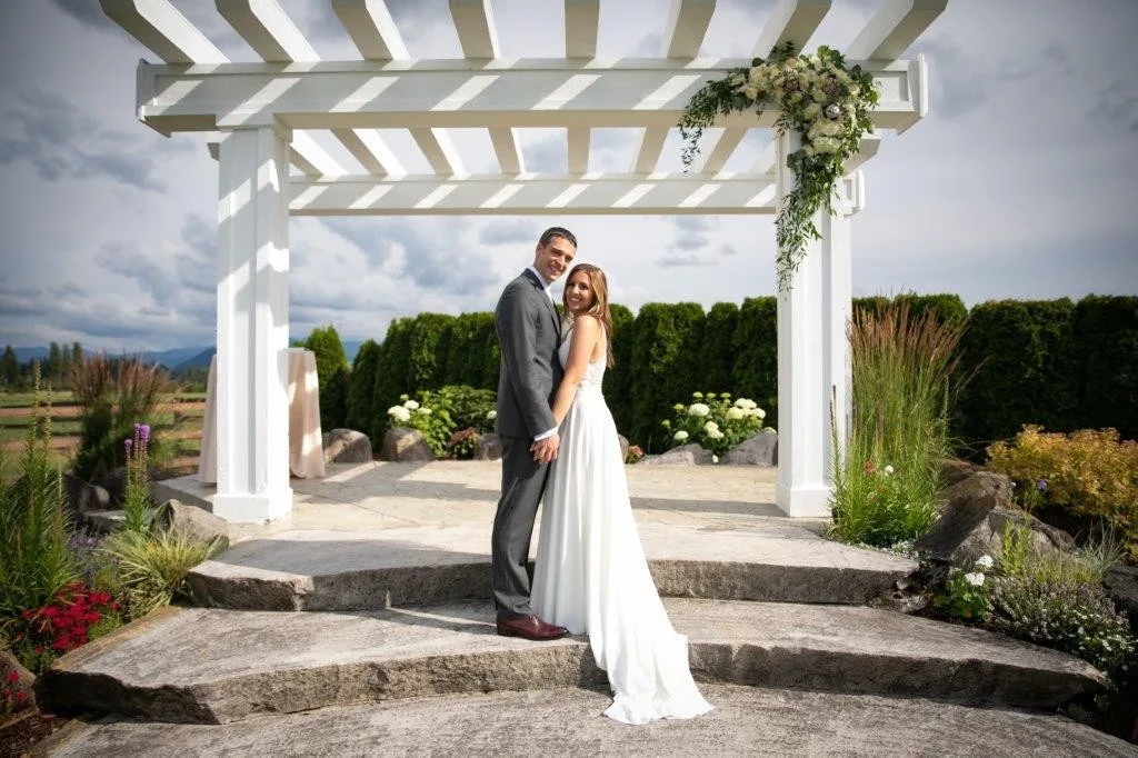 bride groom portrait pergola mountain view manor enumclaw 1 - Frequently Asked Questions Bride and groom embrace under a white floral-adorned pergola at Mountain View Manor wedding venue in Enumclaw Washington near Seattle