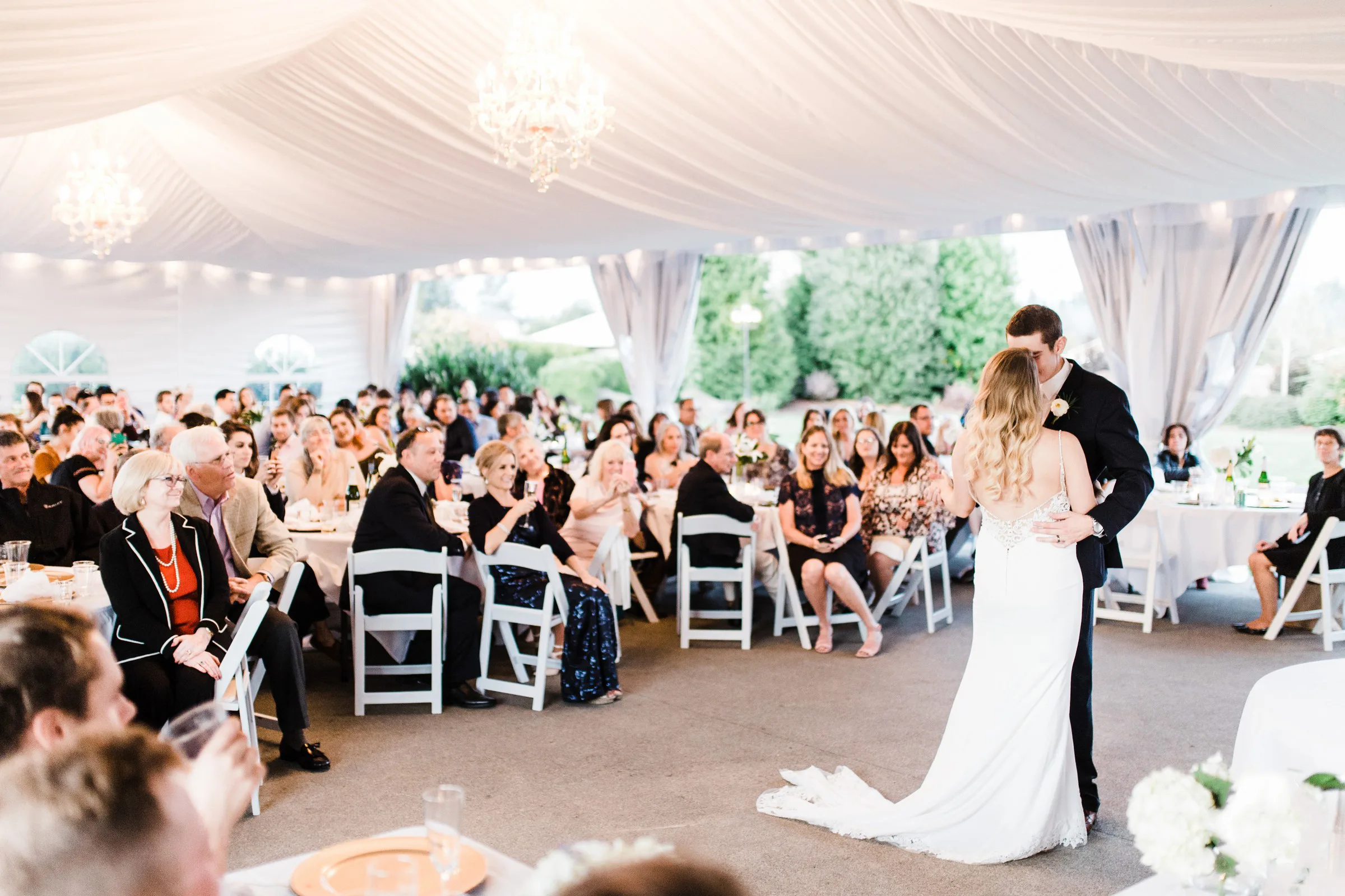 first dance wedding reception mountain view manor enumclaw 3 - Mountain View Manor Bride and groom share their first dance kiss under a white draped tent at Mountain View Manor wedding venue in Enumclaw Washington while guests look on from round tables