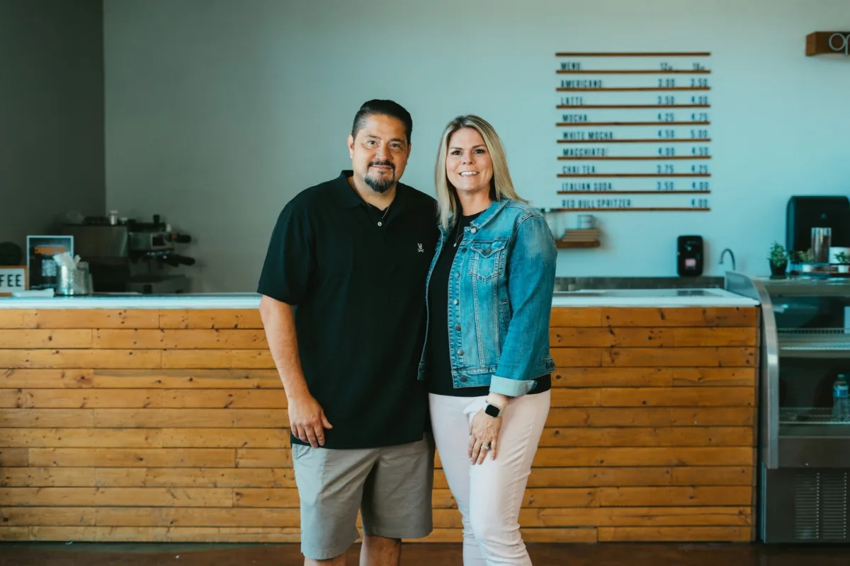 The owners of Mountain View Manor wedding venue stand together smiling in front of a coffee bar