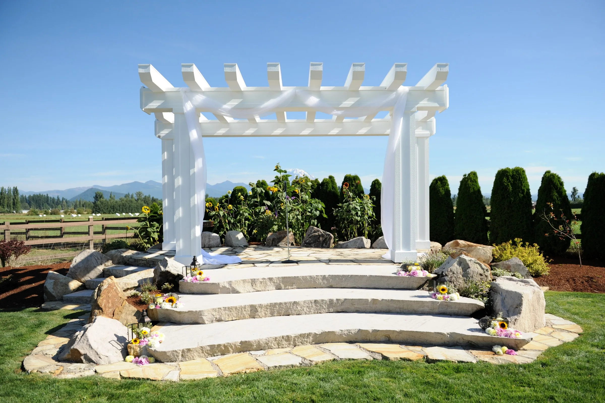 white pergola ceremony space mountain view manor enumclaw - Mountain View Manor White pergola wedding ceremony space with stone steps, sunflowers, and mountain views at Mountain View Manor wedding venue in Enumclaw Washington near Seattle